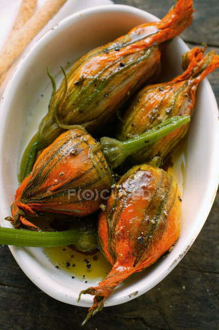 Marinated stuffed courgette flowers in white dish — Stock Photo