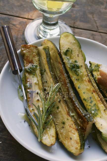 La calabacina adoban - los calabacines fritos con el romero en el plato blanco con el tenedor - foto de stock