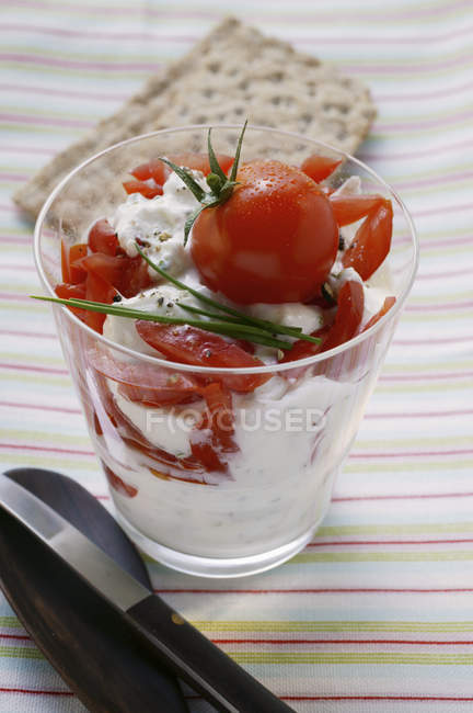 Quark y tomate con pan crujiente en vaso sobre toalla - foto de stock