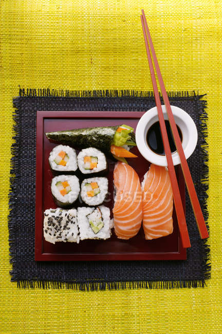 Assorted sushi on red platter — Stock Photo
