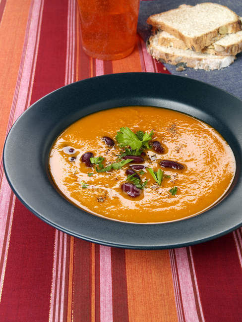 Гарбузовий суп з квасолею в чорній тарілці — стокове фото