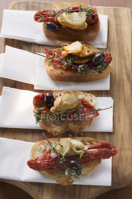 Crostini with seafood and dried tomatoes on wooden desks with napkins — Stock Photo