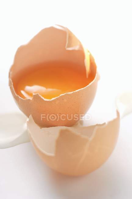 Vista de cerca de un huevo abierto roto en la superficie blanca - foto de stock