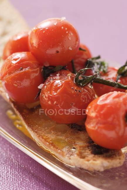 Tomates cerises cuites sur du pain blanc sur un plateau sur une surface violette — Photo de stock
