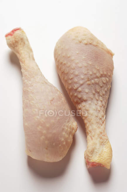 Vista de cerca de dos patas de gallina Poularde en la superficie blanca - foto de stock