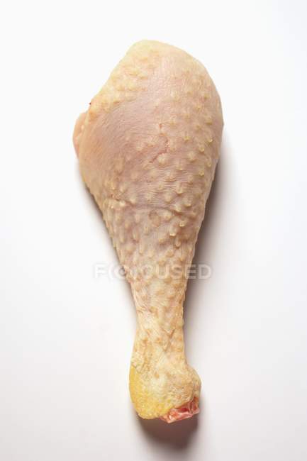 Closeup view of one raw poularde leg on white surface — Stock Photo