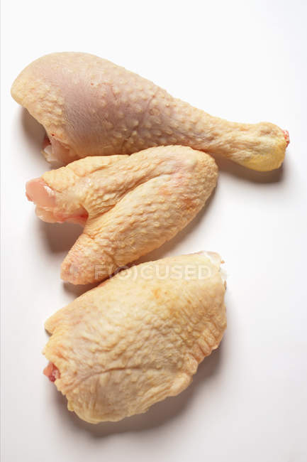 Vista de primer plano de la pierna de gallina poularde, el ala y el pecho en la superficie blanca - foto de stock
