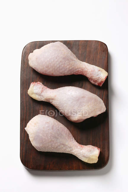 Patas de pollo crudo en la tabla de cortar - foto de stock