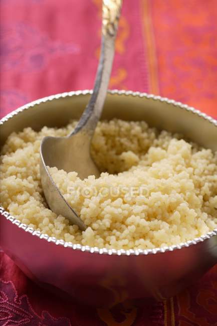 Close up view of couscous with spoon in silver bowl — стоковое фото