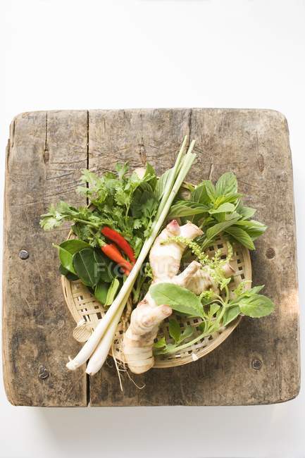 Herbes et épices thaïlandaises fraîches dans le panier sur la surface en bois — Photo de stock