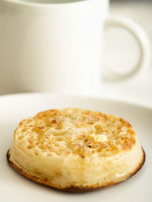 Vista close-up de crumpet torrado com manteiga no prato branco — Fotografia de Stock