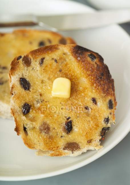 Vue rapprochée de petits pains grillés avec des raisins secs et morceau de beurre — Photo de stock
