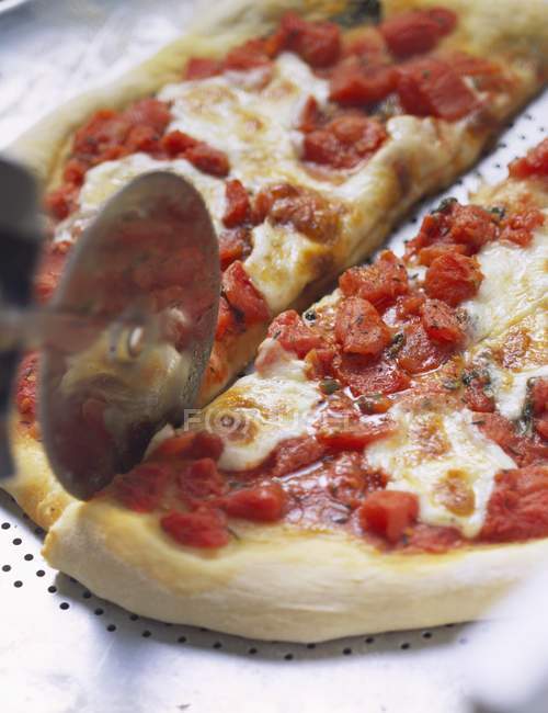 Pizza con cortador de pizza - foto de stock