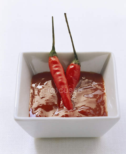 Red sauce and two chili peppers — Stock Photo