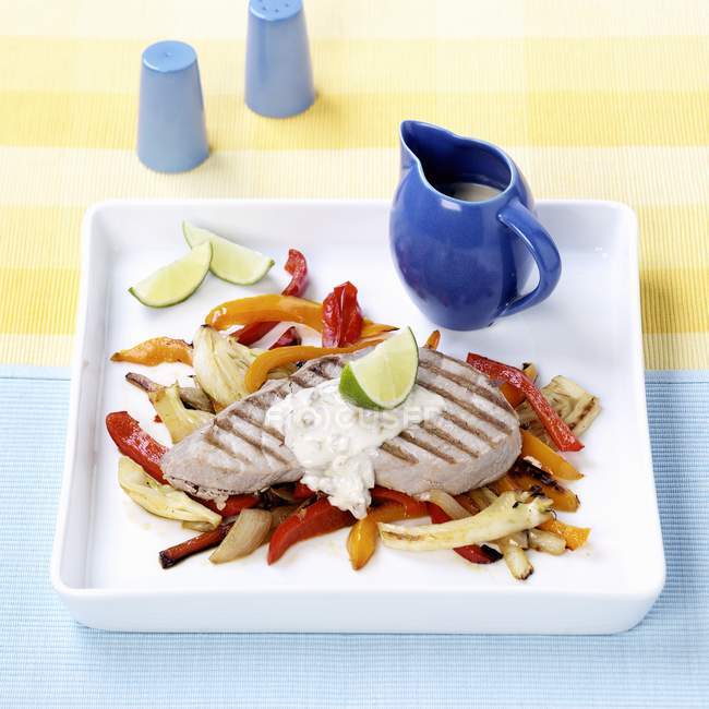 Grilled veal escalope on vegetables on white platter — Stock Photo