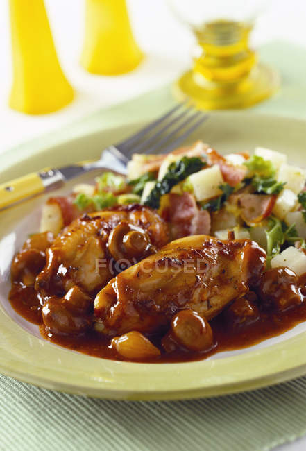 Кролик з грибним соусом, картоплею та соусом в тарілці з виделкою над столом — стокове фото