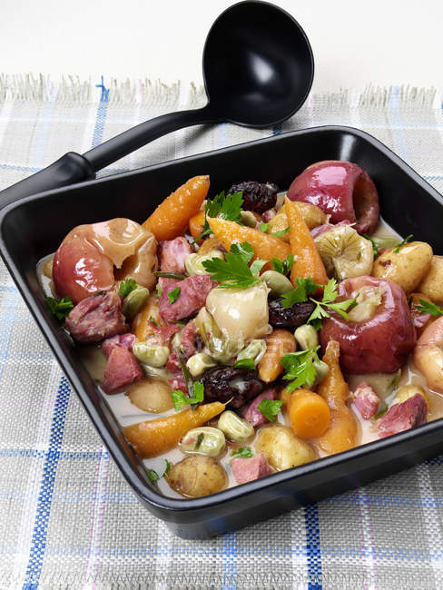 Stew of ham, apples and vegetables in baking dish on checkered fabric — Stock Photo