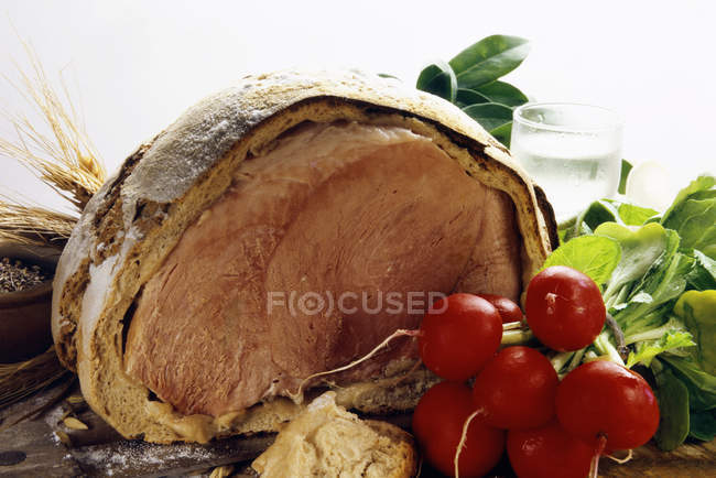 Ham baked in bread dough, a bunch of radishes in front on white background — Stock Photo