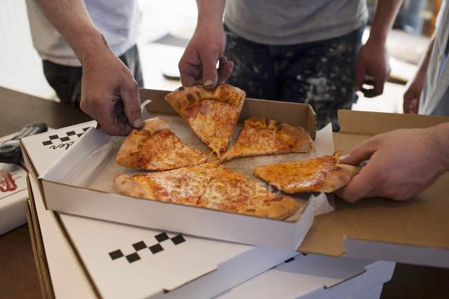 Arbeiter nehmen ein Stück Pizza — Stockfoto