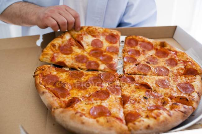 L'homme prend un morceau de pizza — Photo de stock