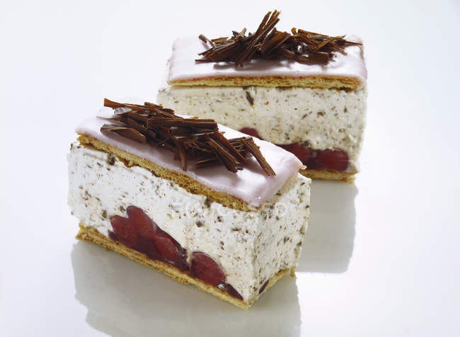 Вид крупным планом ломтиков вишневого пирога с шоколадом на белой гладкой поверхности — стоковое фото