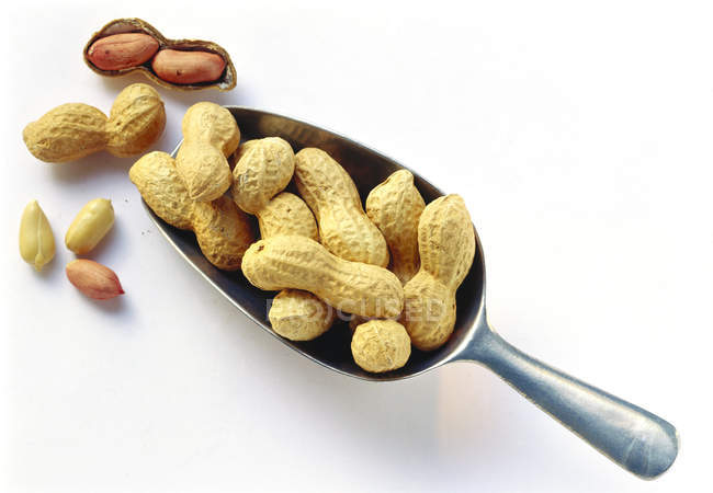 Amendoins em e ao lado colher — Fotografia de Stock