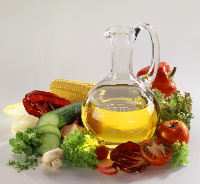 Natura morta con olio e insalata ingredienti su sfondo bianco — Foto stock
