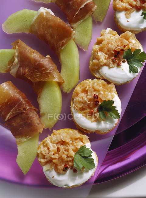 Snacks de salmón y rodajas de melón con jamón - foto de stock