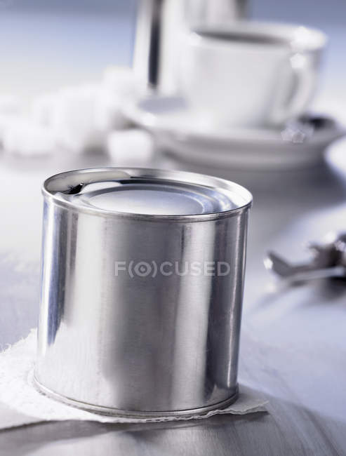 Nahaufnahme von Konservenmilch mit Kaffeetasse auf dem Hintergrund — Stockfoto