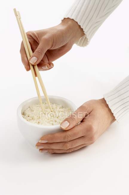 Womans holding chopsticks in bowl of rice — Stock Photo