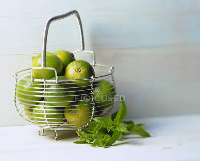 Several limes in wire basket — Stock Photo