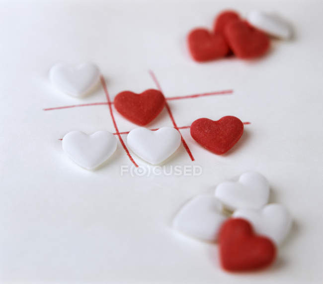 Closeup view of white and red grape sugar hearts in cells on white surface — Stock Photo