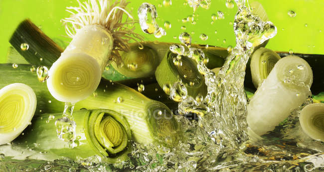 Leek slices falling into water — Stock Photo