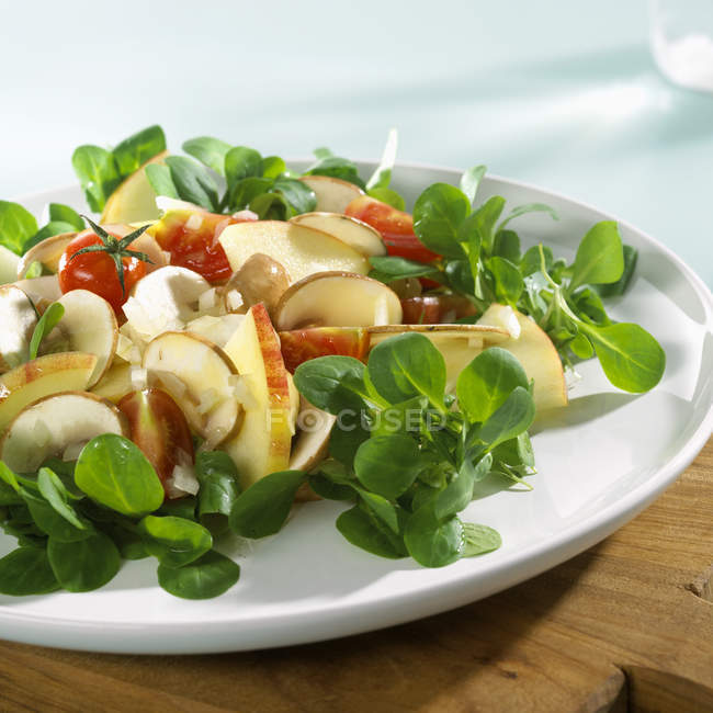 Кукурудзяний салат з яблуком, помідорами та грибами на білій тарілці — стокове фото