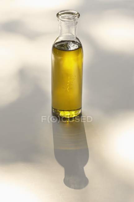 Vista elevada de uma garrafa de vidro de óleo na superfície branca — Fotografia de Stock