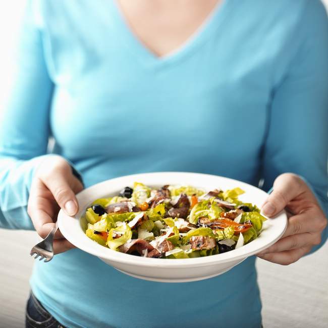 Frau hält Salat mit gegrilltem Gemüse auf Teller in der Hand, Mittelteil — Stockfoto