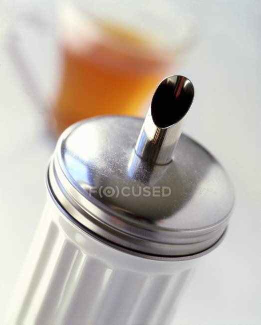Vista de primer plano de la batidora de azúcar y vaso de té en el fondo - foto de stock