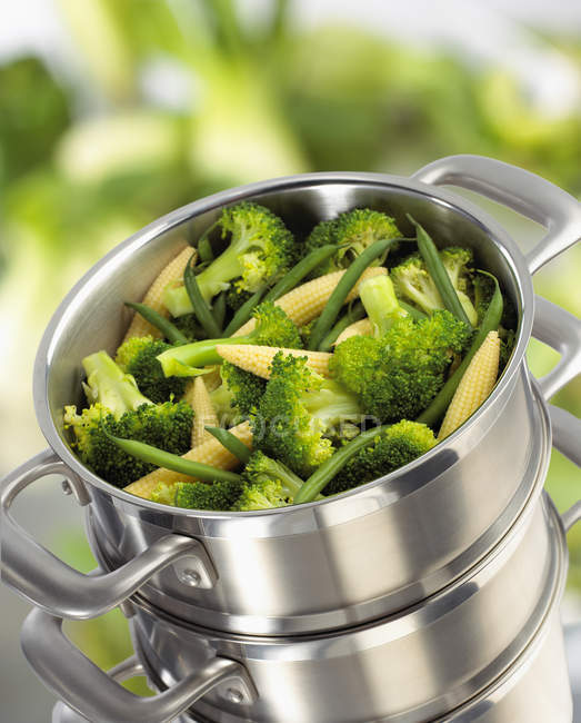 Broccoli, baby corn-cobs and green beans in steaming pan — Stock Photo