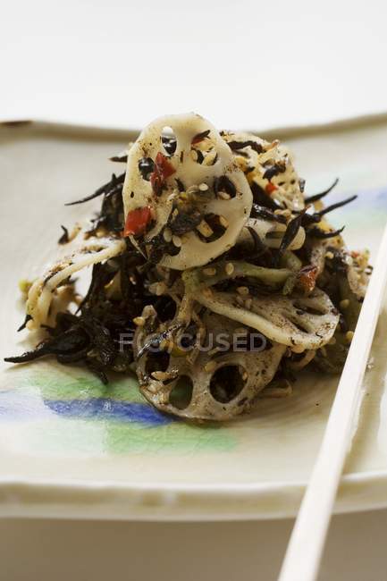 Ensalada de algas con raíces de loto y sésamo en plato - foto de stock
