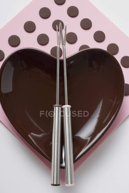 Gros plan vue de dessus de bol en forme de coeur avec fourchettes à fondue — Photo de stock