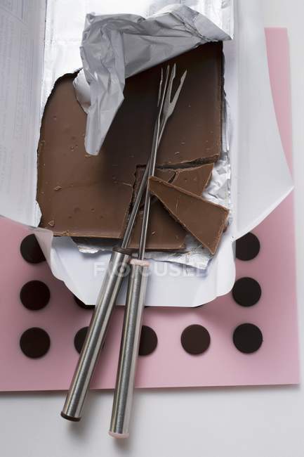 Vista de primer plano de la barra de chocolate rota con tenedores de fondue - foto de stock