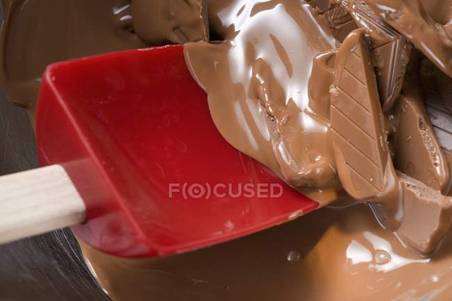Vue rapprochée de la fusion du chocolat sur cuillère à mélanger rouge — Photo de stock