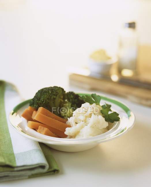 Verduras al vapor en plato blanco sobre superficie blanca - foto de stock
