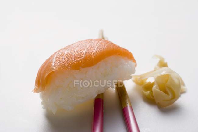 Nigiri sushi with salmon on chopsticks — Stock Photo