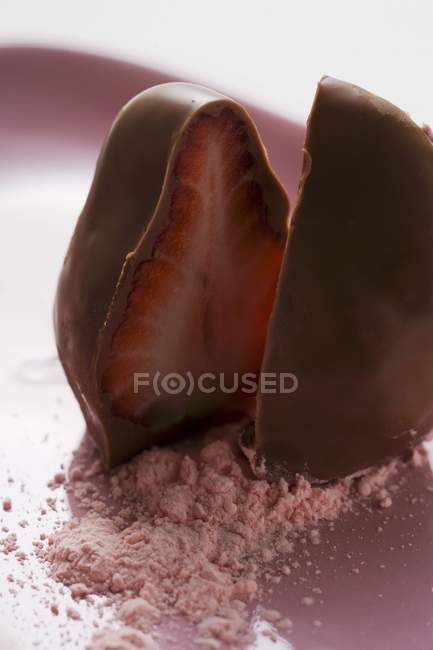 Fresa sumergida en chocolate a la mitad - foto de stock
