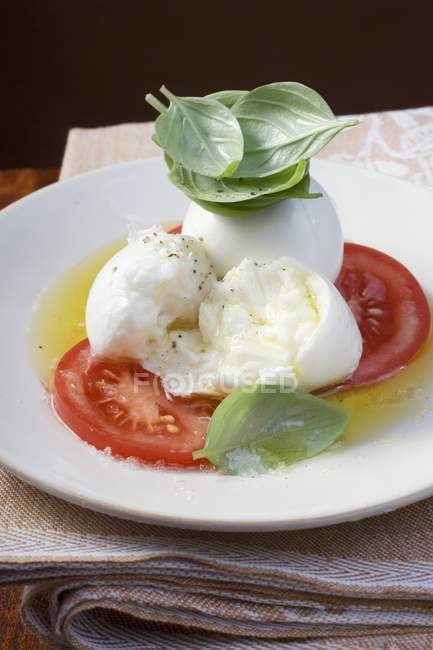 Insalata caprese - Tomatoes with mozzarella and basil  on white plate — Stock Photo
