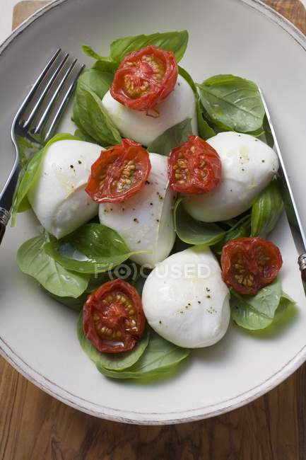 Insalata caprese - Tomates com mussarela e manjericão sobre placa branca com garfo — Fotografia de Stock