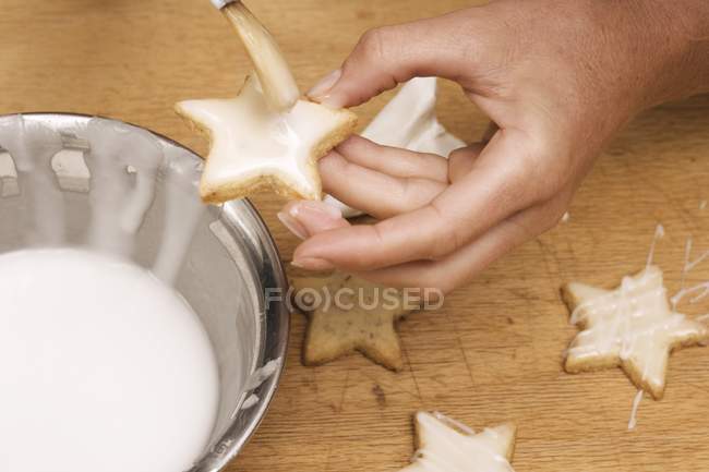Hände bürsten Kekse mit Zuckerguss — Stockfoto