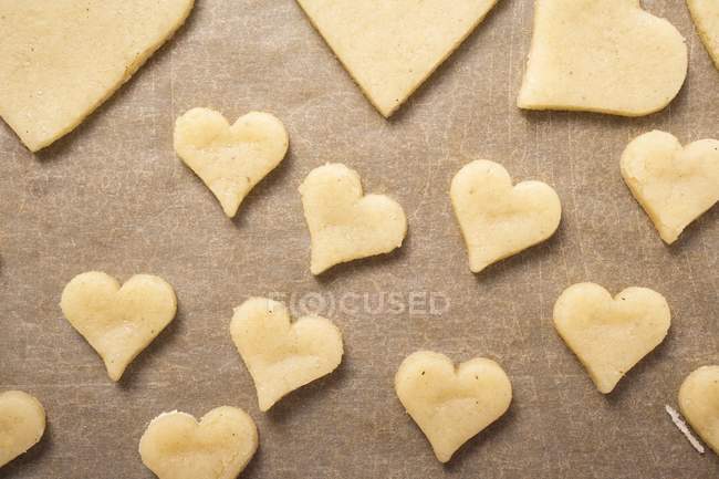 Вид сверху на вырезанные печенье в форме сердца на выпечке пергамент — стоковое фото
