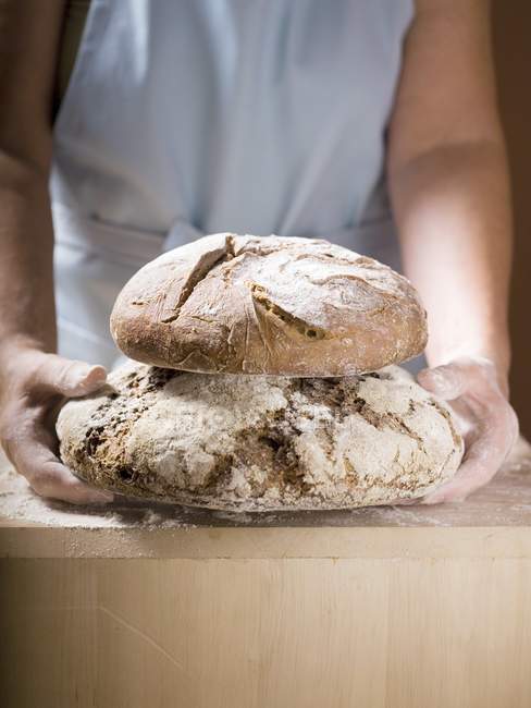 Woman holding two loaves of Bauernbrot — Stock Photo